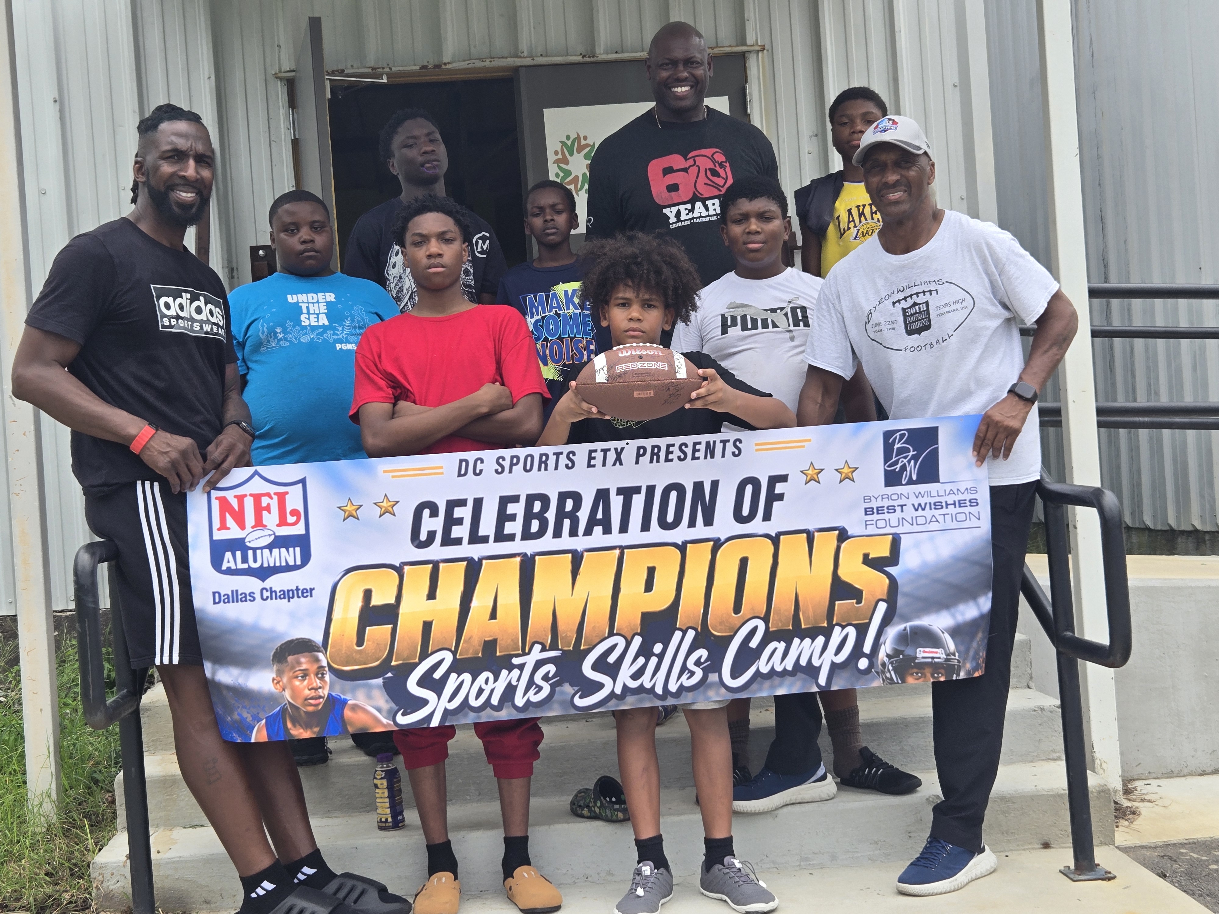 Young athletes and mentors posing with a Celebration of Champions sports camp banner