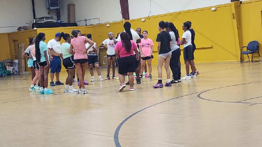 Young athletes and mentors gathered in a circle on a gym court