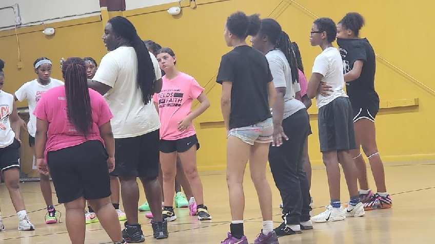 Young athletes and mentors talking together on a gym court